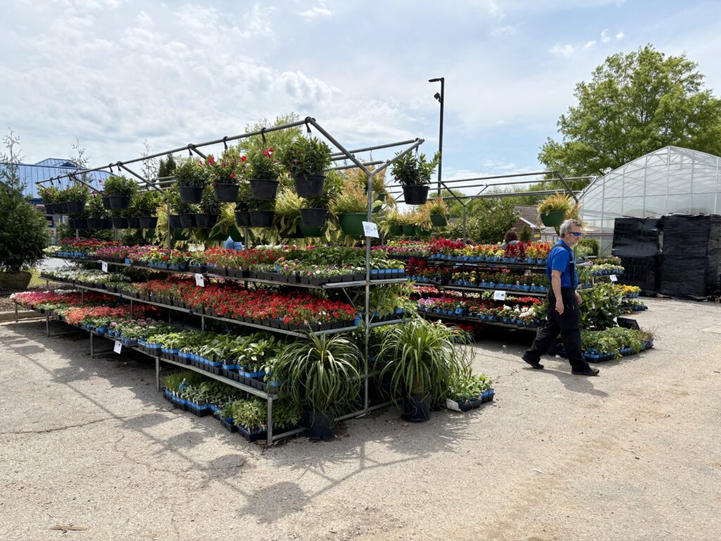 A man walks past a display of plants and flowers at The Enchanted Forest Garden Center in Madison, Alabama