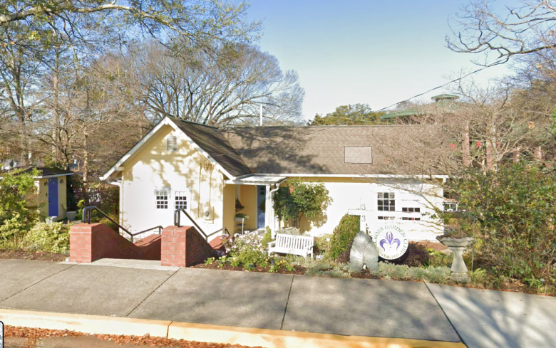 Norcross Garden Club building exterior with landscaped entrance, brick steps, and circular sign on a tree-lined street in downtown Norcross, Georgia