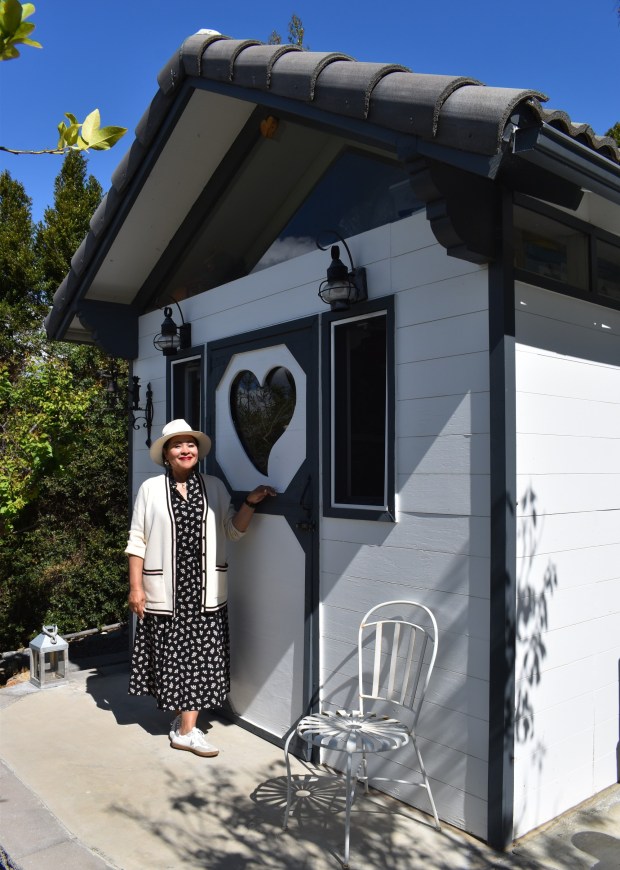 Ramona Garnier outside one of three cottage-style buildings constructed to blend into the garden while providing storage for essential garden items and decorations. (Elizabeth Marie Himchak)