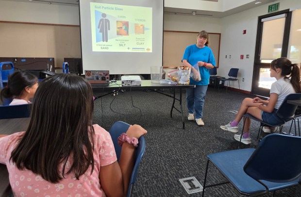 Master Gardener Niki Vollrath, right, talked about soil particle sizes during her STEAM Kids activity at Poway Library. (Julie Gallant)