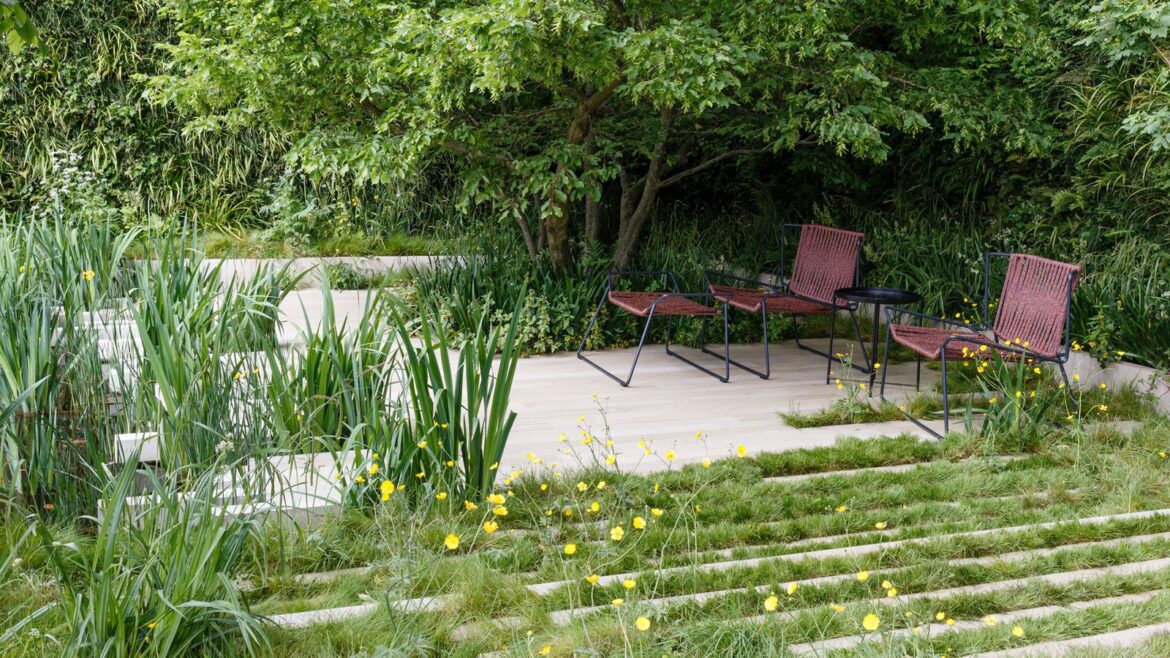 garden design with pale hardscaping and natural planting, with garden chairs and table, and trees