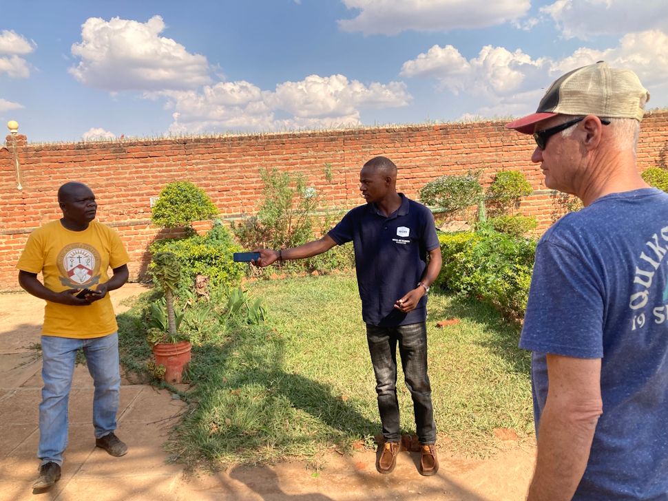 Africans with a member of Well of Plenty in front of one of the gardens