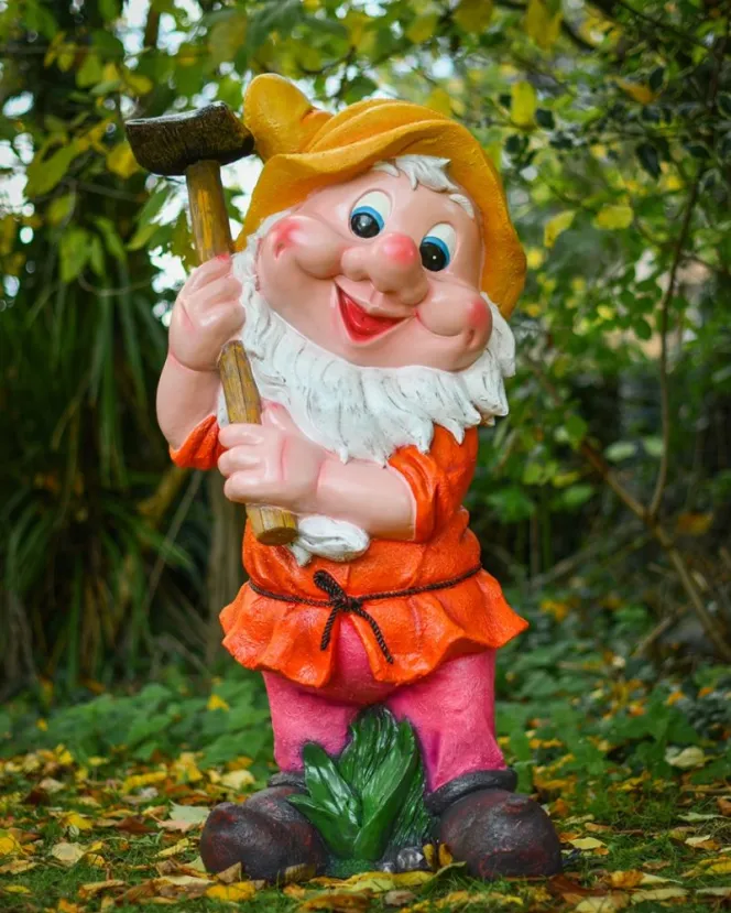 A fibreglass garden gnome, named Walt, holding a hammer and smiling, painted in bright oranges, pinks, and yellows.