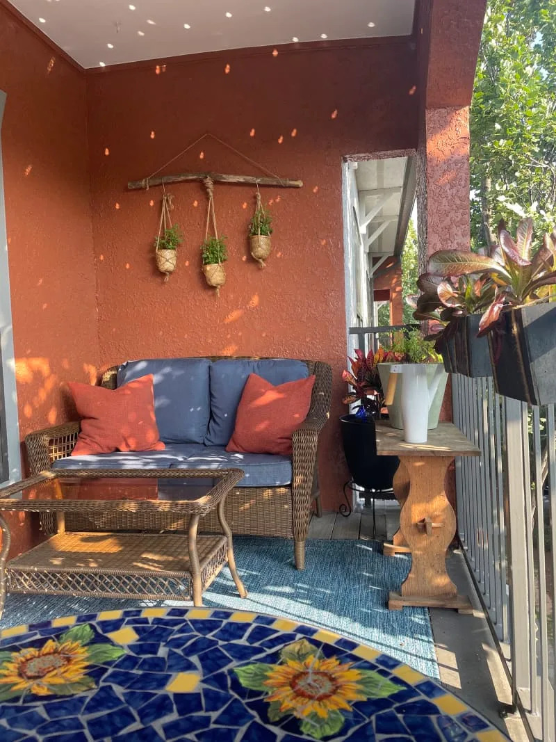 Brick red deck/patio with loveseat, coffee table, and plants