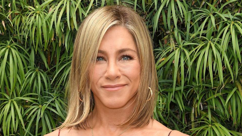 Jennifer Aniston surrounded by green plants.