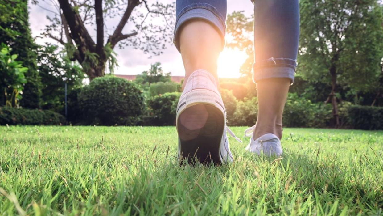 Woman jeans and sneaker shoes on Sunset walking in garden