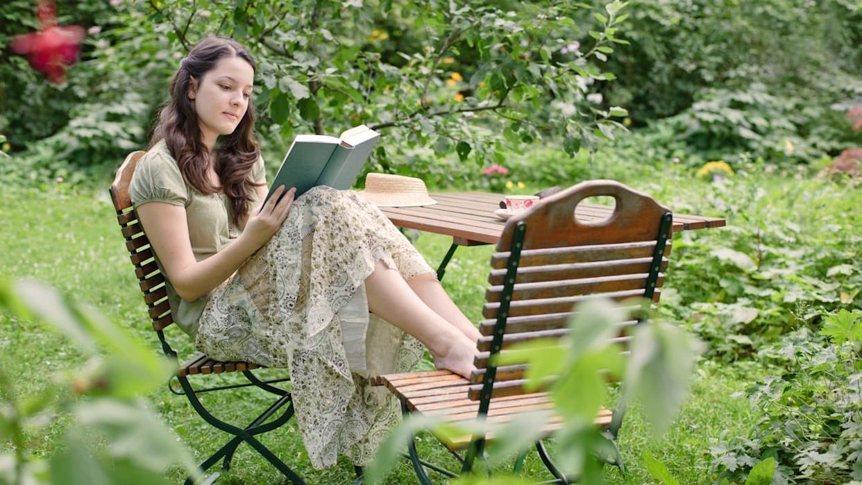 A woman sitting in the garden reading a book.