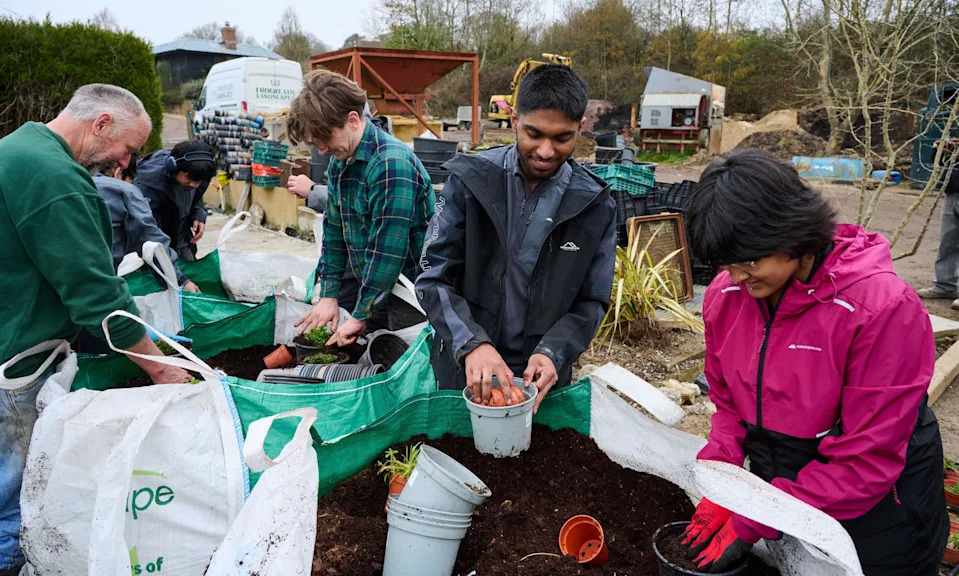 Six gardeners with pots and earth in a garden centre