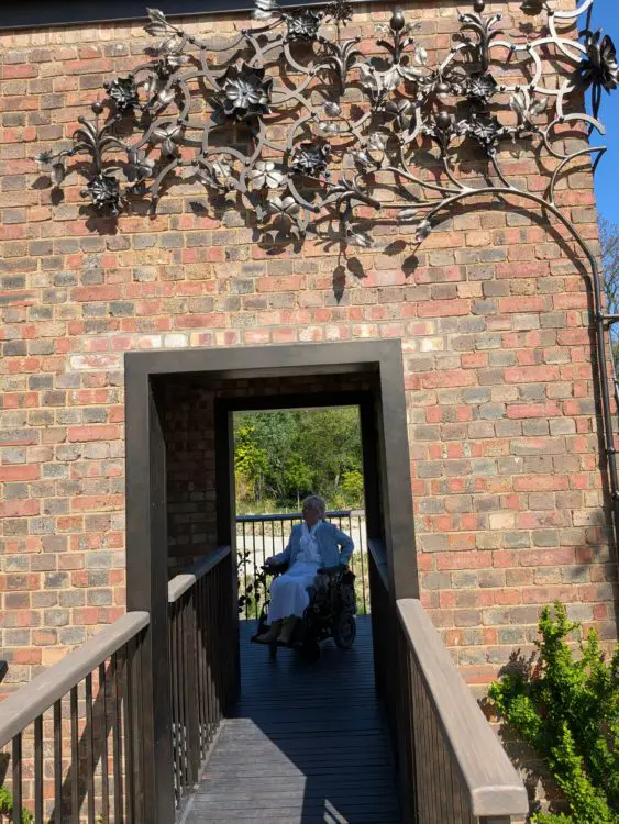 Wheelchair user on an accessible bridge inside the brick water tower, beneath decorative metalwork panels.