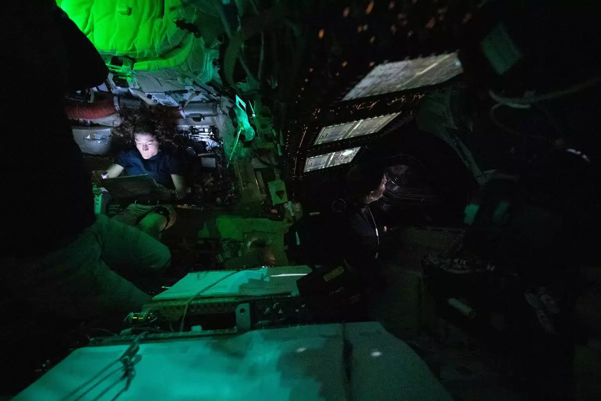 This image provided by NASA, astronaut Christina Koch is illuminated by a screen inside the darkened Orion spacecraft on the third day of the agency's Artemis II mission on Friday, April 3, 2026. (NASA via AP)