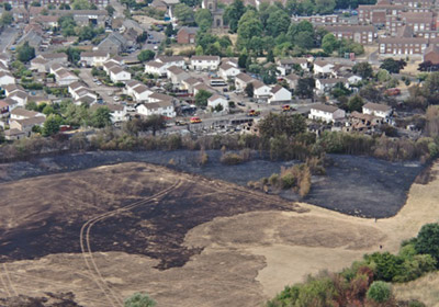 London Fire Brigade urges Londoners to spring clean gardens to help prevent grass fires An aerial view of burnt grassland next to residential streets. The homes closest to the grassland have been destroyed.
