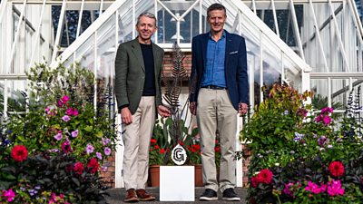 Michael Connolly and Robert Russell stood outside a green house surrounded with plants and holding the greatest gardens trophy