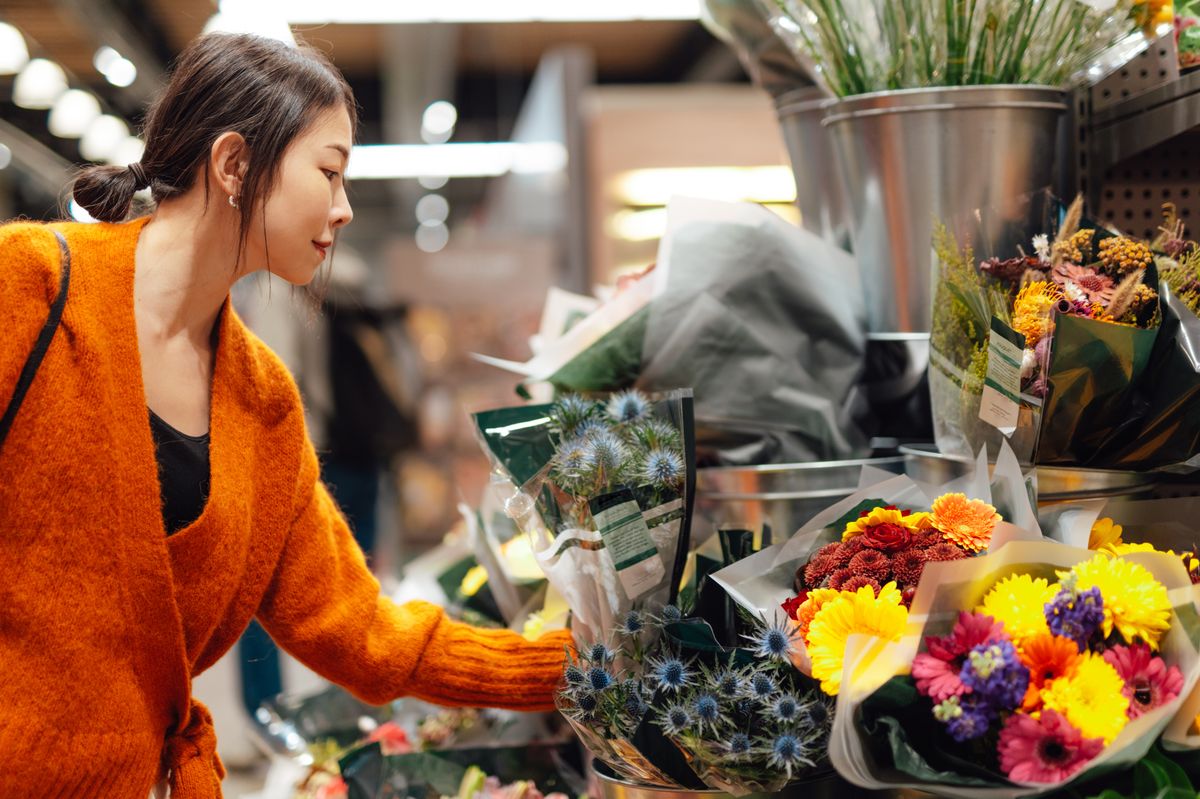 woman picking out flowers in supermarket