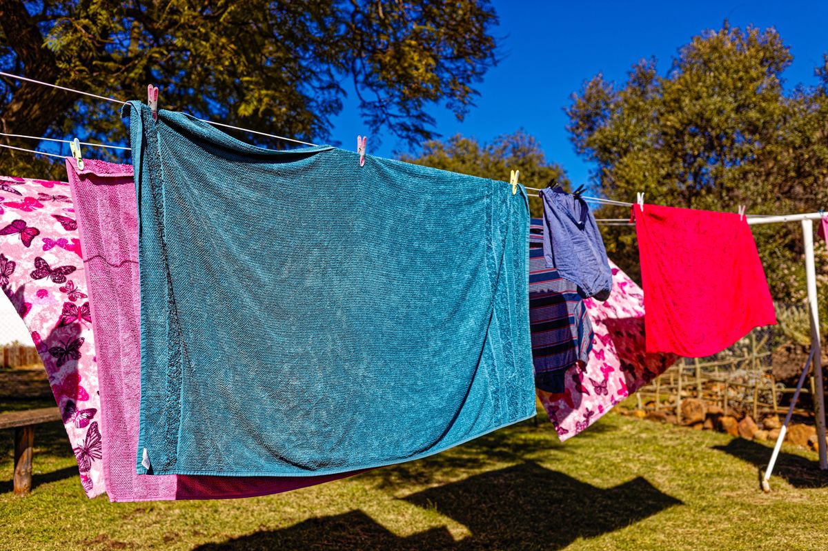 Multi-colored washing hanging on clothes line in a garden with green grass on a sunny day and blue sky
