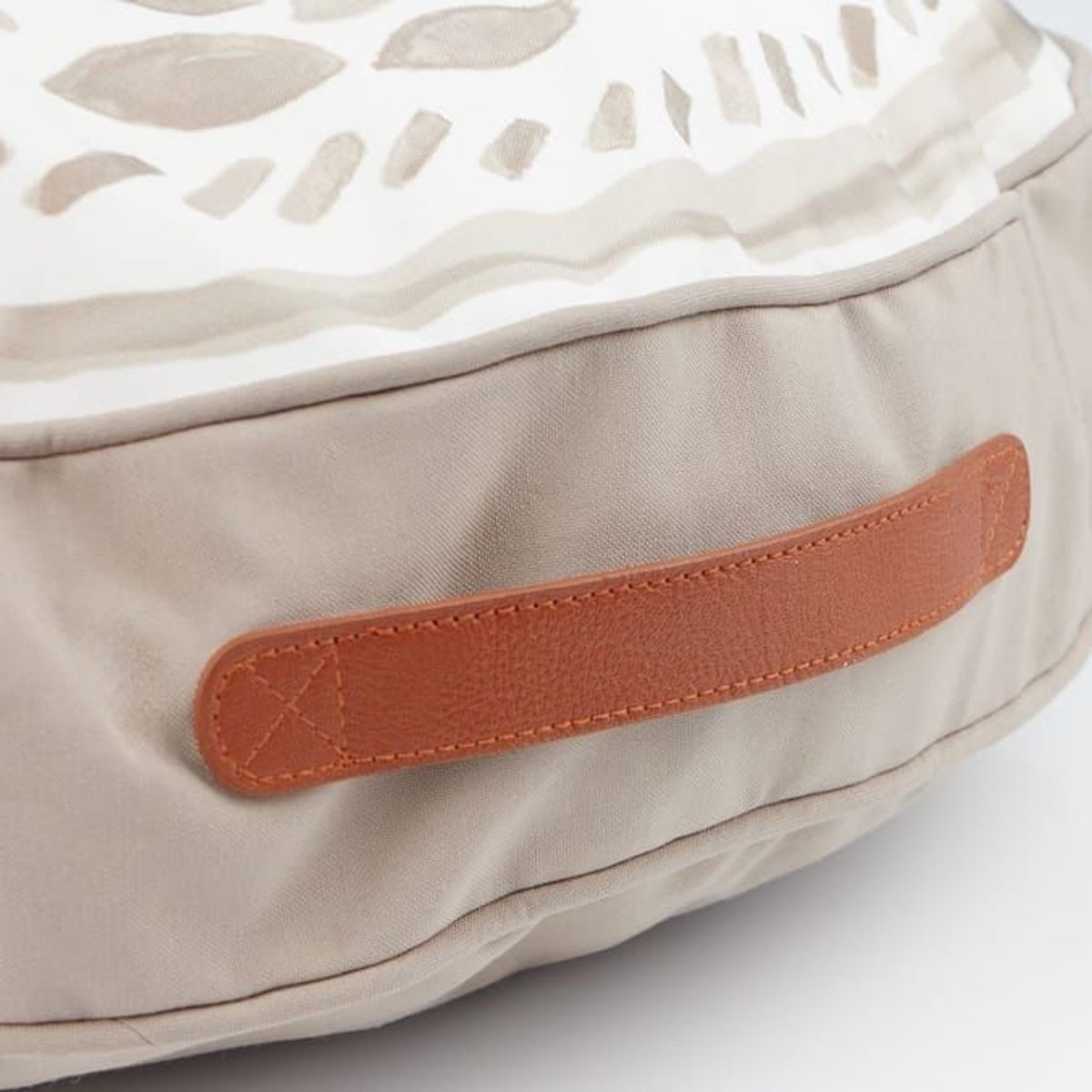 A close up of a tan coloured handle on the side of the beige cushion