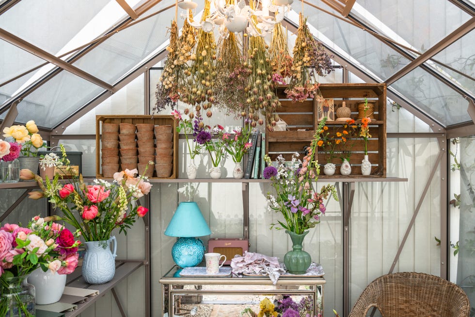 A floral workspace in a greenhouse filled with various flowers and tools for gardening.