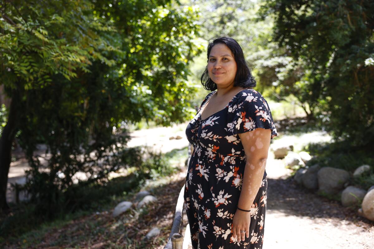 A woman stands surrounded by green.