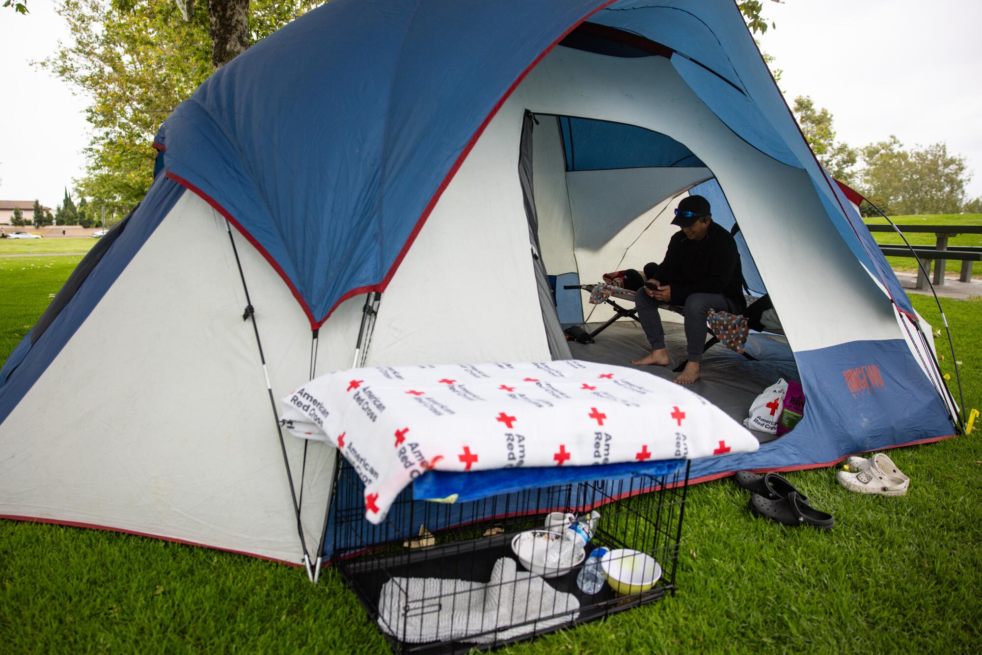 Henry Nguyen sits on a cot inside his tent outside the Freedom Hall shelter in Fountain Valley.