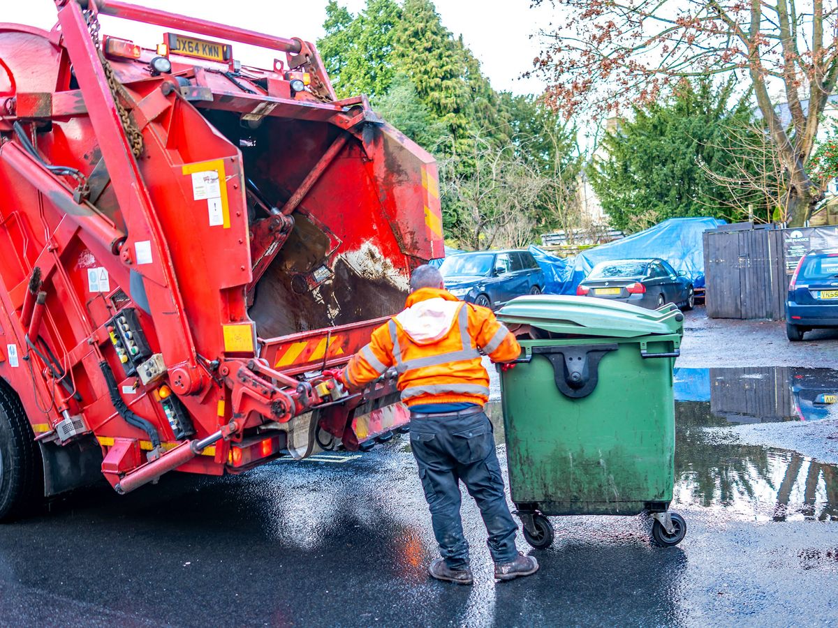 Bakewell, Derbyshire, UK – November 26 2019: Refuse collector preparing wheelie bin for emptying in to the dumpster lorry