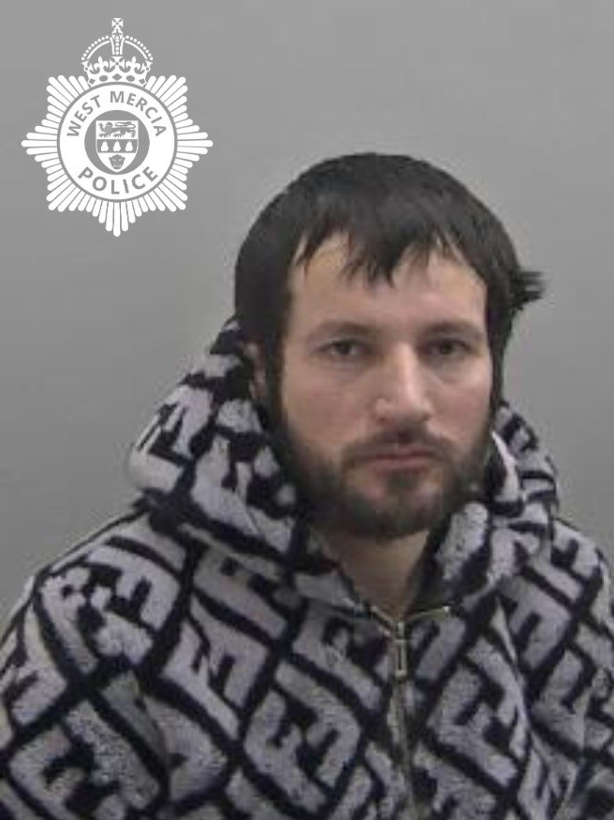 Police custody image of Festim Ahmetaj, 35, pictured in a Fendi FF grey and black hooded jacquard jacket with black hair and a black beard.