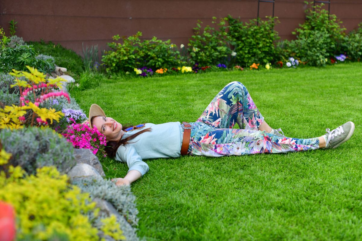 Portrait of beautiful mid age woman with sun hat and long hair resting at her garden