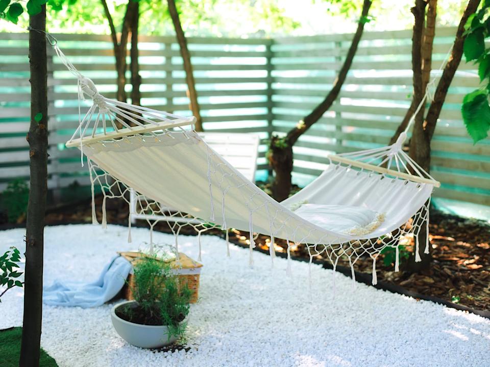 white boho Hammock hanging on tree in summer garden.