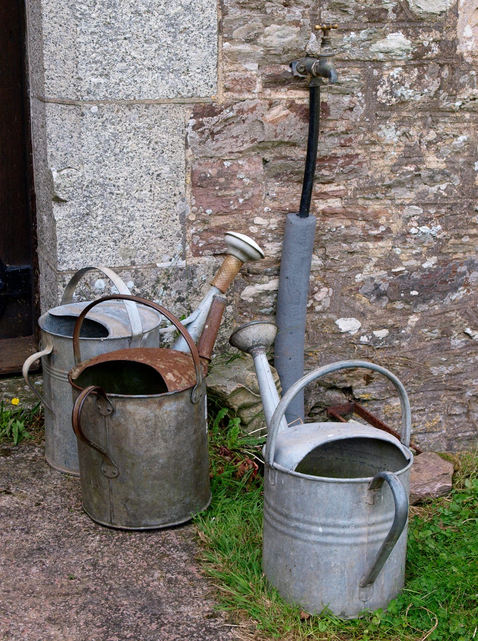 Three watering cans by a tap in a graveyard, Devon, UK Three watering cans by a tap in a graveyard, Devon, UK