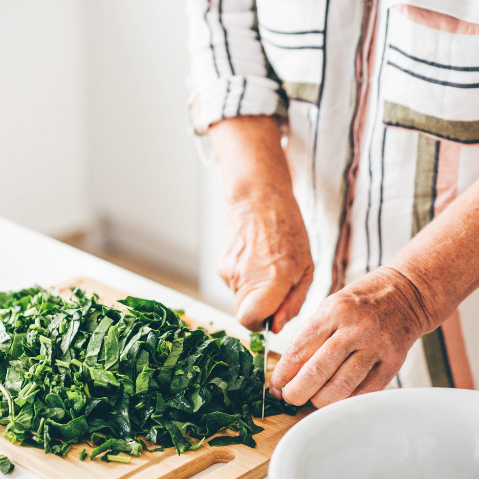 Cheerful senior woman cooking in the kitchen. Woman making spinach cake. cheerful senior woman cooking in the kitchen. woman making spinach cake.