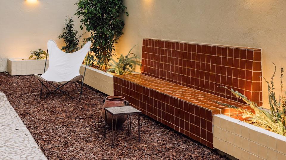 A small woodchip garden with a tiled, rust colored outdoor bench. 