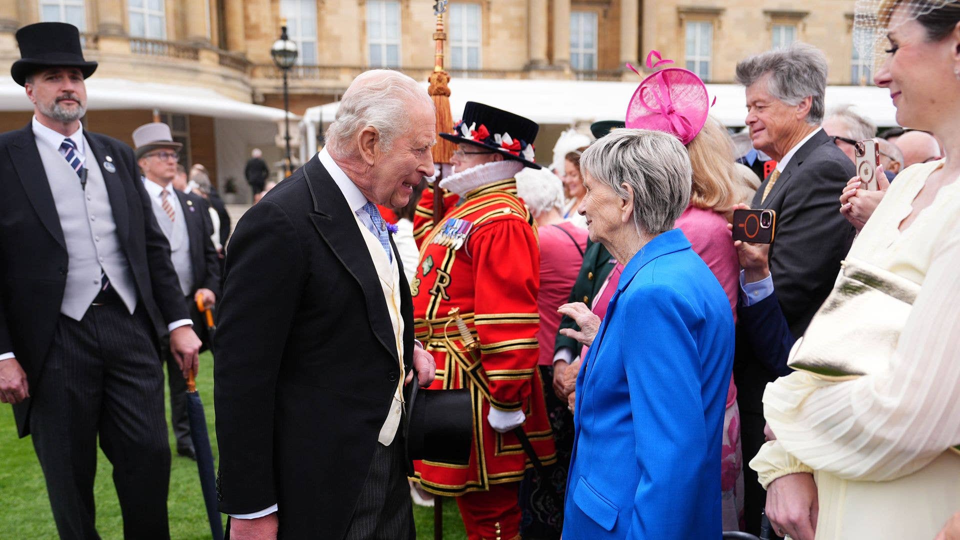 King Charles talking with an elderly woman at a garden party