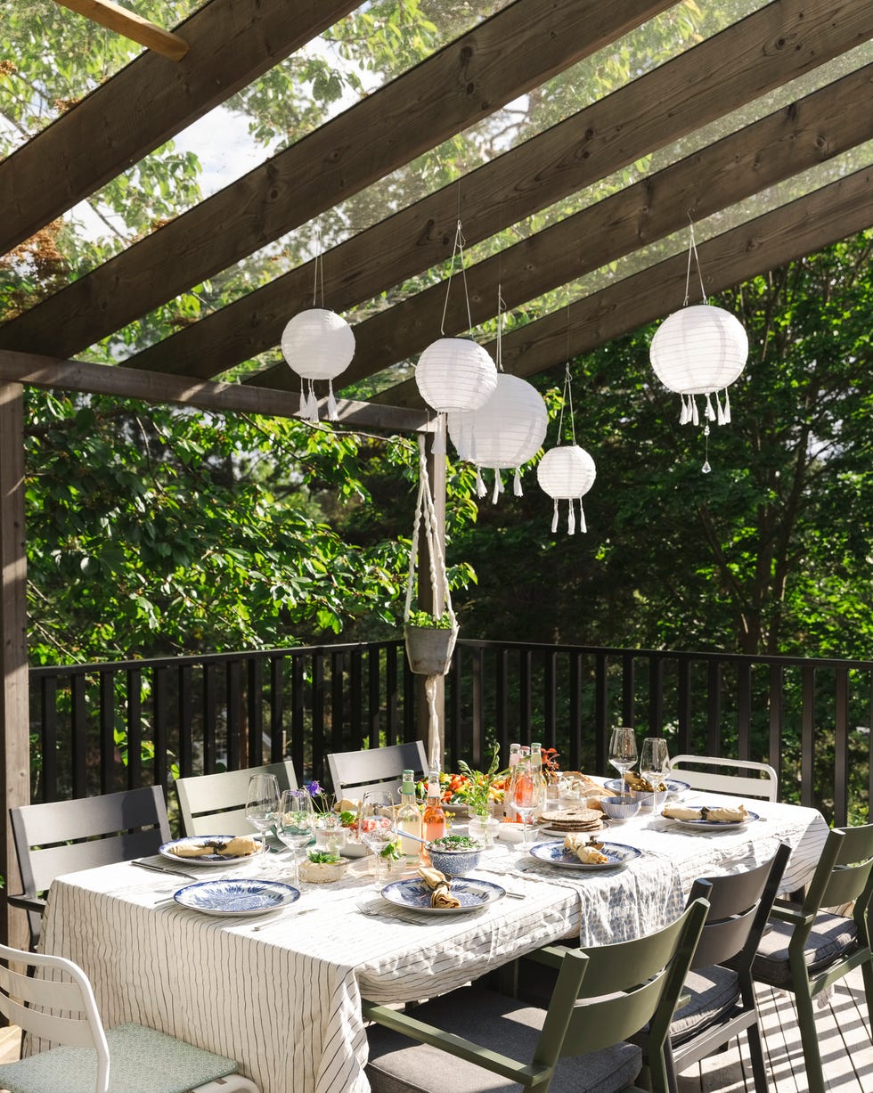 Lanterns hanging over dining table at patio outdoor dining setup with table and chairs under a pergola