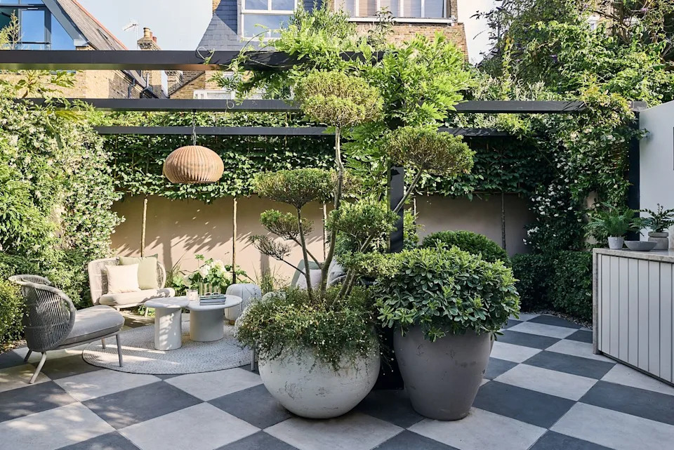  A modern garden filled with plants with a large checkerboard floor. 