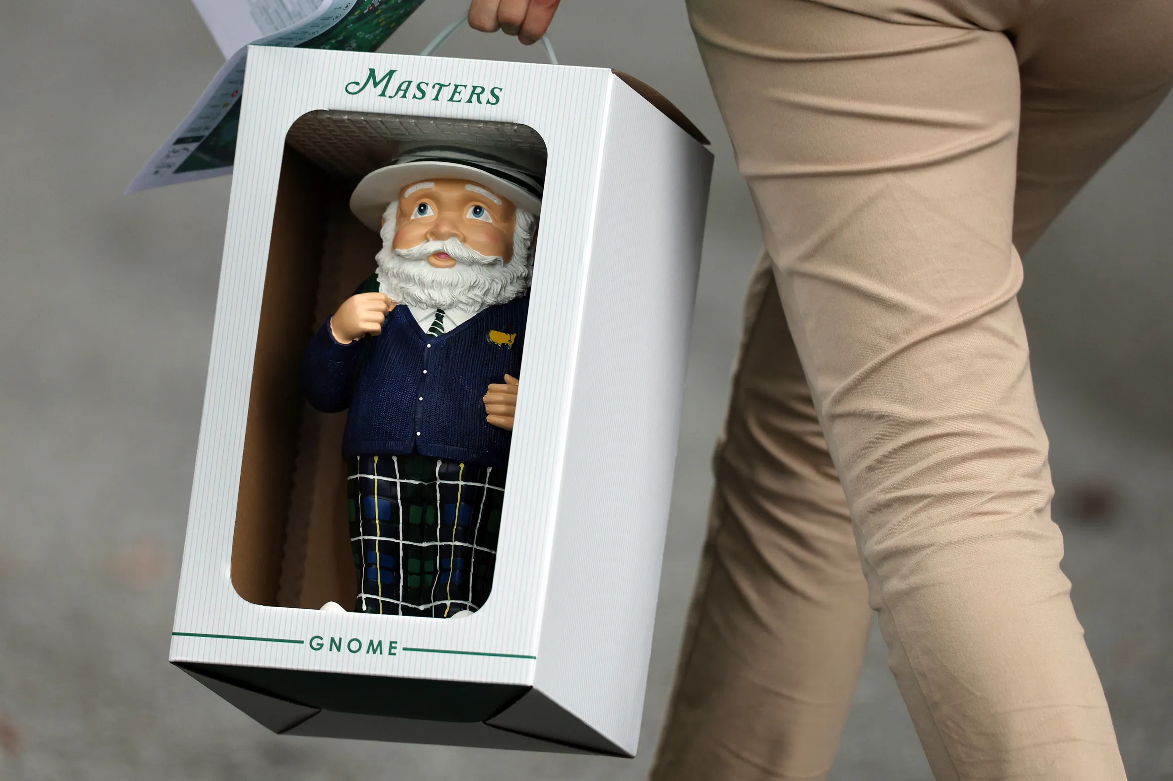 A person carries a Masters Gnome in a white box.