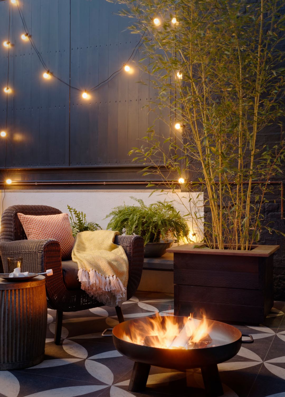 picture of garden set up with bamboo fire pit and chair with added festoon lighting
