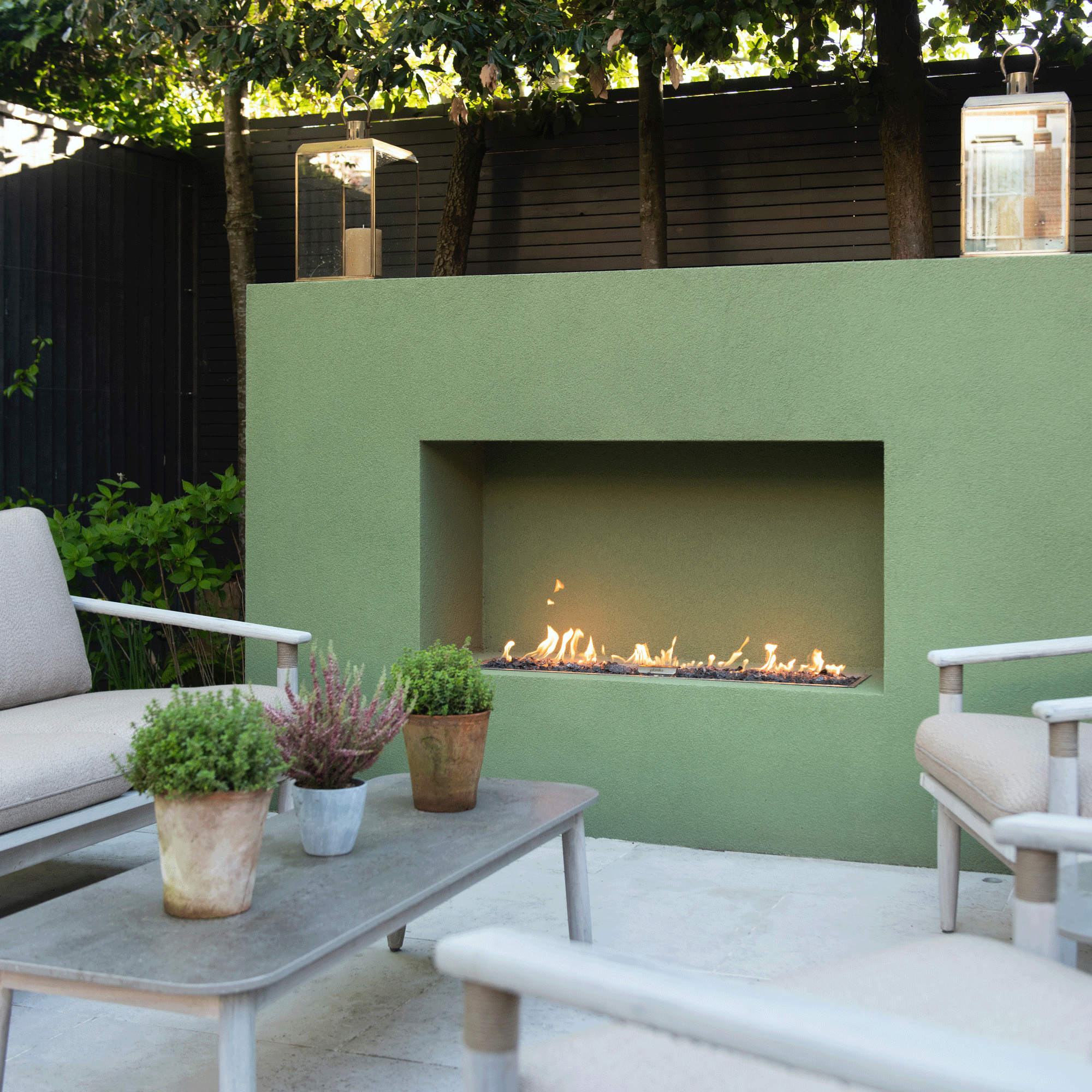 a garden with a patio area and large green outdoor fireplace and seating in front