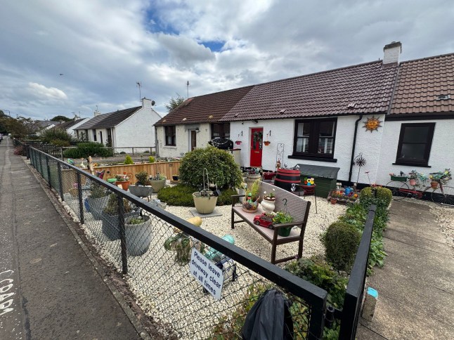The wooden planter which has sparked a row between neighbours. // A retired widow became embroiled in a bizarre neighbour planning row - after being accused of 'spending hours' attending to her new planter. Jane Higgins, 74, had the planter installed in the front garden of her semi detached home and spends her time tending to the plants, flowers and ornaments within it. But her family were shocked when they were told they needed to apply for retrospective planning permission for structure - as a neighbour had issued a complaint. Among the concerns raised by the one objector were that it overshadows their privacy "as the neighbour spends hours attending to their plants." Photo released 17/05/2026
