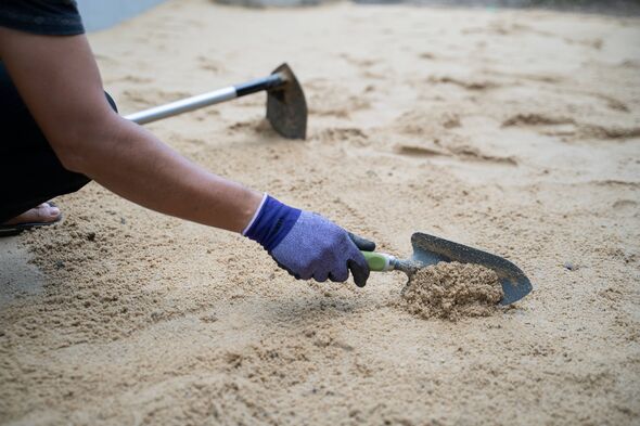 A person spreading sand across their garden A person spreading sand across their garden