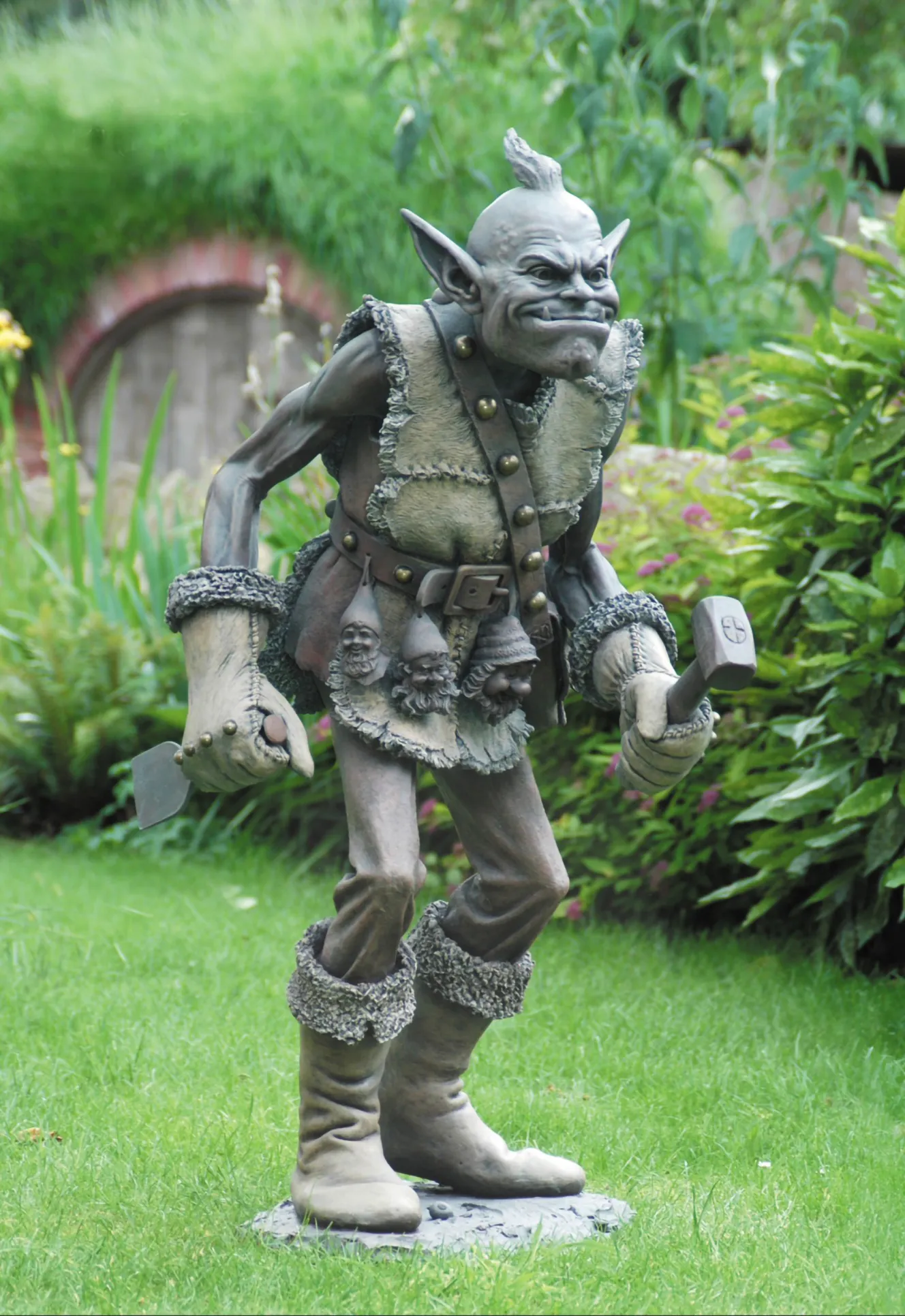Bronze sculpture of a gnome hunter with an axe and hammer, and gnome heads on his belt.