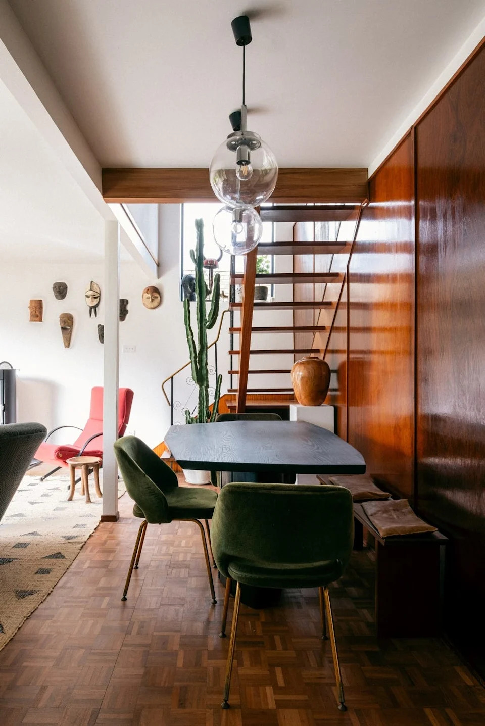 a modern interior featuring a dining space with green seats and a wooden staircase