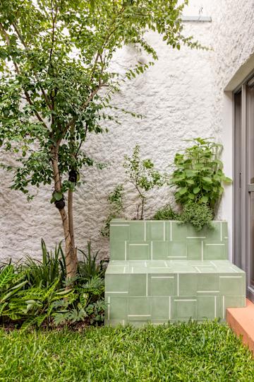 a green tiled outdoor bench with a planted top