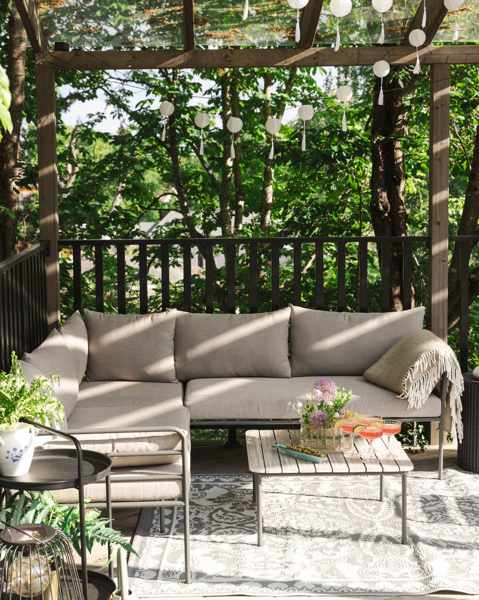 Drinks on table by empty sofa at patio on sunny day outdoor seating area with a sectional couch and decorative elements