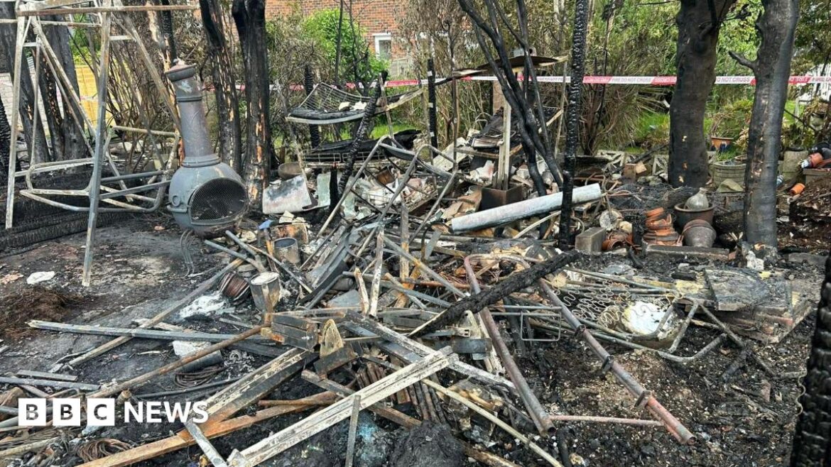 Neighbours rally after fire sweeps through Crawley gardens A pile of burned wreckage sat on a charred surface in a garden. The remains of some trees, a garden swing and a garden stove can be seen amongst the ruins.