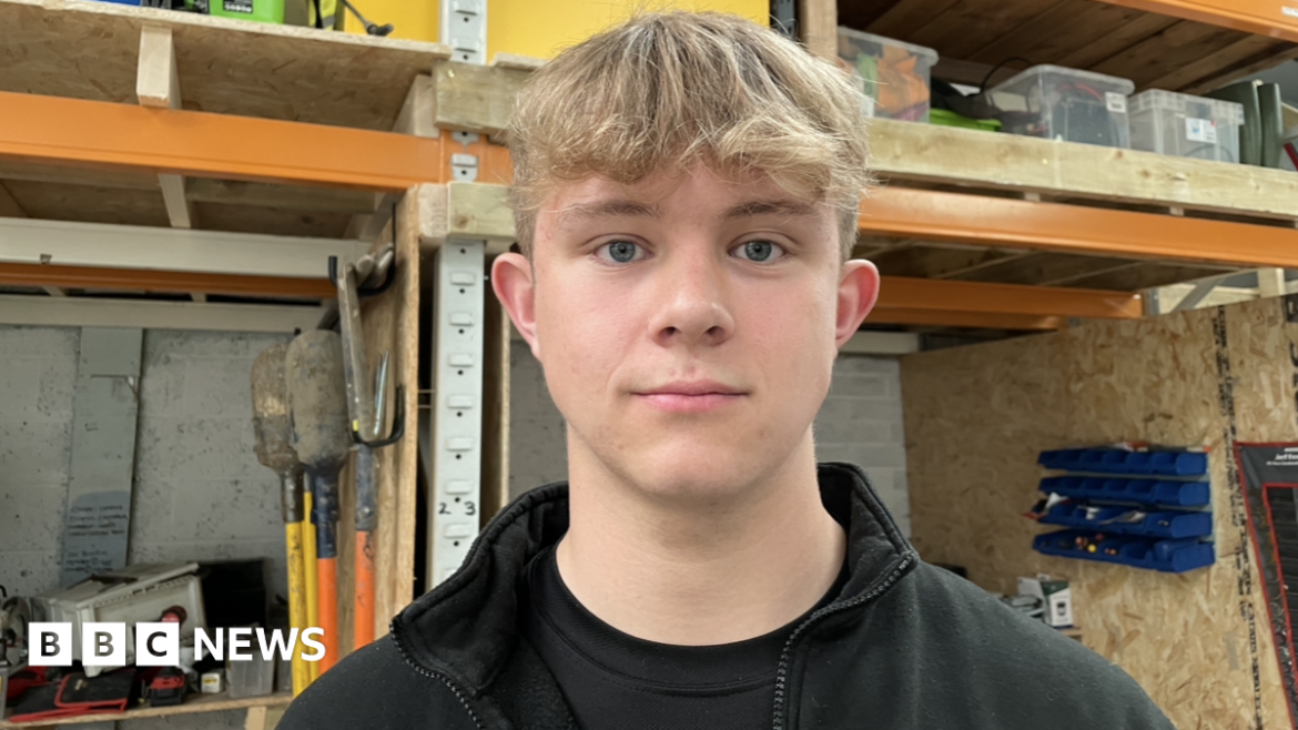 Barnard Castle garden business owner loses £30k after tool theft Jack Roberts is looking straight into the camera with a neutral expression. He has short blonde hair with a curly fringe, and is wearing a black t-shirt and black fleece. In the background behind him is the interior of his tool storage unit, where gardening tools including shovels are being stored.