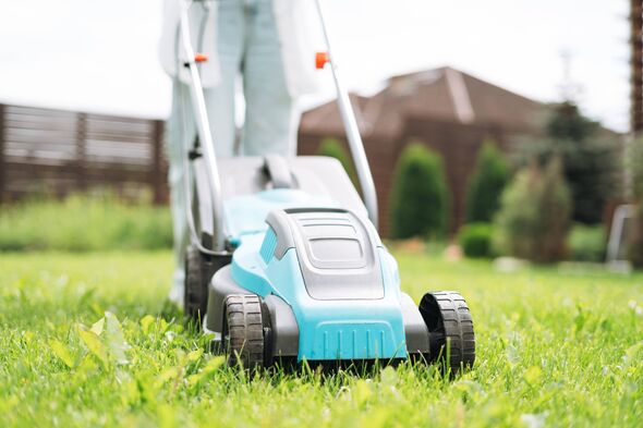 Crop photo of young woman in casual clothes mowing grass with lawn mower in backyard of house Crop photo of young woman in casual clothes mowing grass with lawn mower in backyard of house