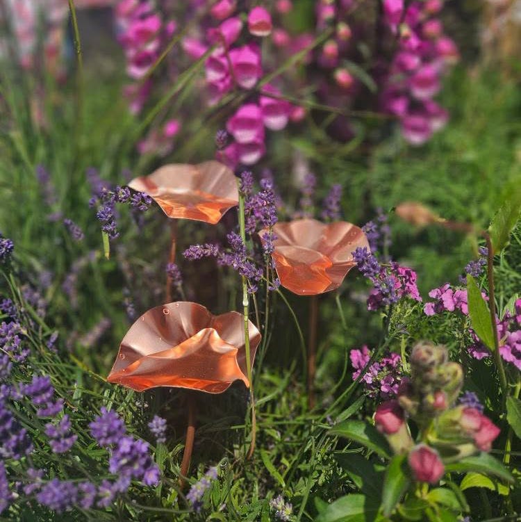 Coppercolored sculptures resembling flowers among vibrant wildflowers copper bee drinkers among flowers