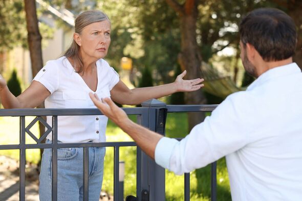 Emotional neighbours having argument near fence outdoors Emotional neighbours having argument near fence outdoors