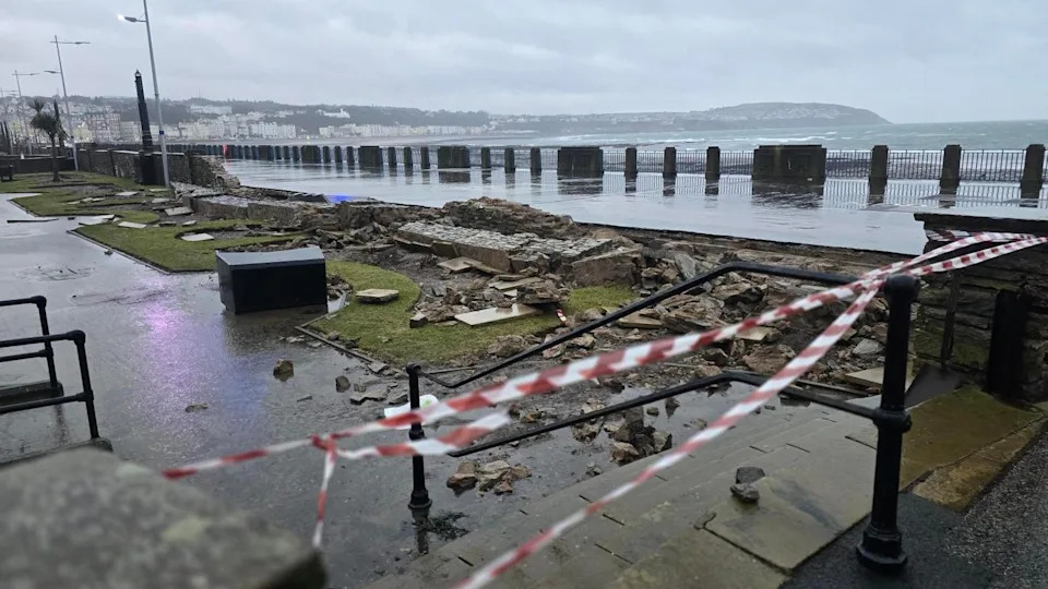A section of the promenade with part of a stone wall brought down. It is cordoned off with red-and-white tape.