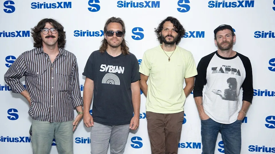 Four band members standing side by side.
