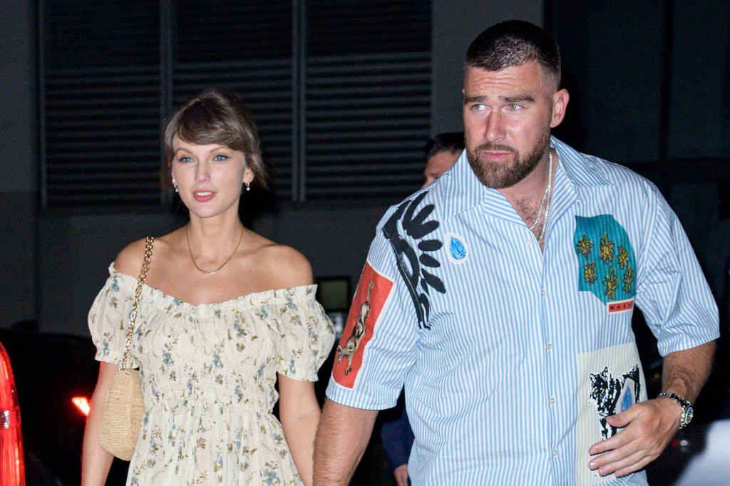 Taylor Swift and Travis Kelce holding hands while walking.