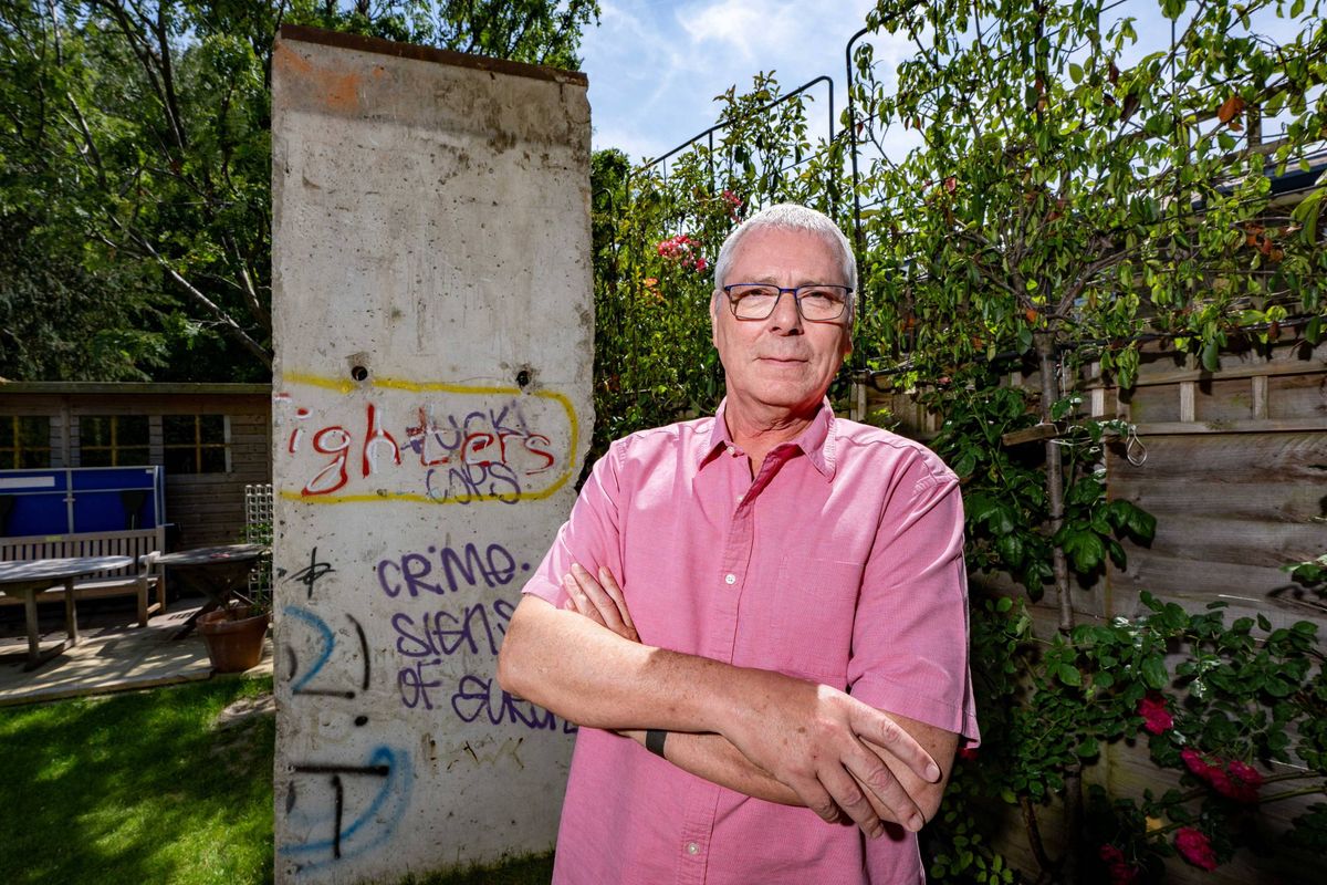 A man standing in front of a chunk of the Berlin Wall